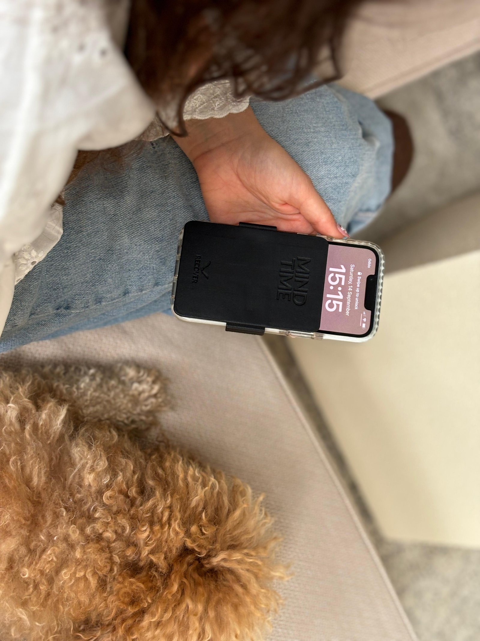 Holding the phone with ReCover placed, dog resting nearby.